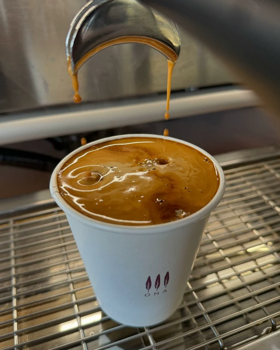 Fresh espresso pouring into a takeaway cup